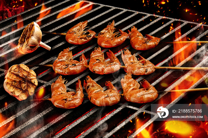 Barbecue bbq grilled delicious roasted shrimps on wooden skewers with halves of garlic. Flaming fire