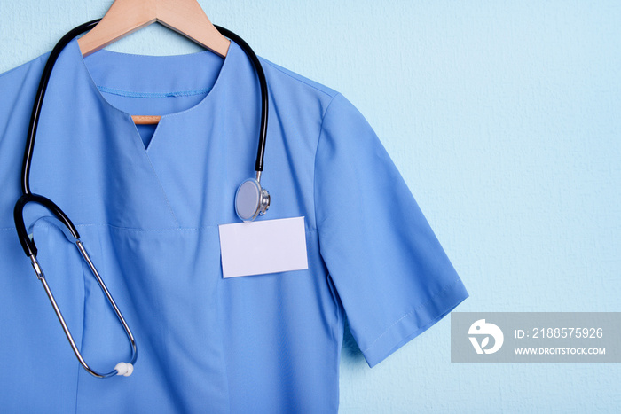 Doctor shirt with stethoscope on hanger on blue background