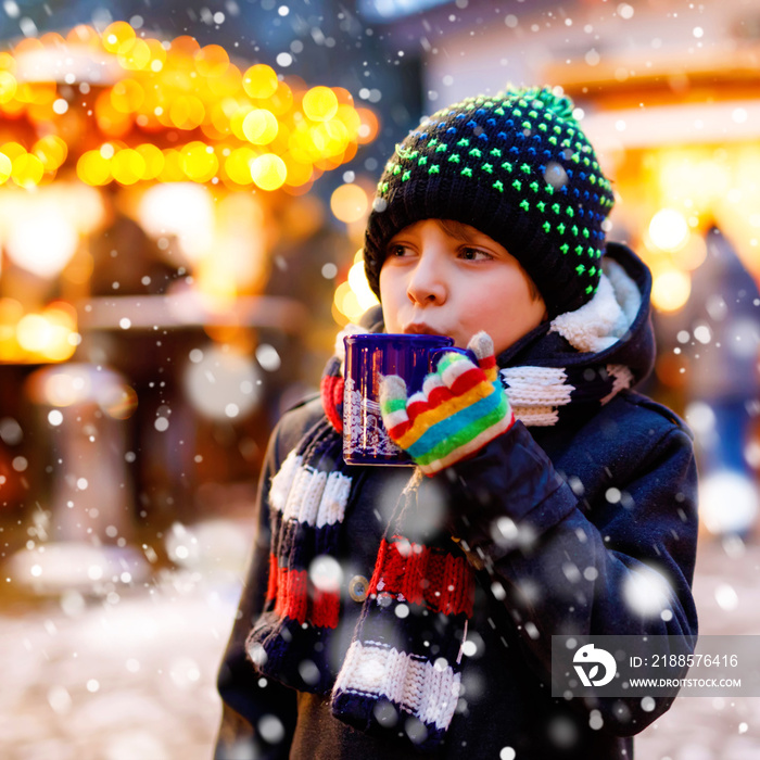 Little cute kid boy drinking hot children punch or chocolate on German Christmas market. Happy child