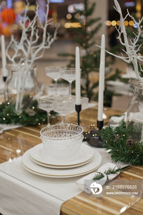 Festive christmas table setting with white plates and candles and holiday season decor.