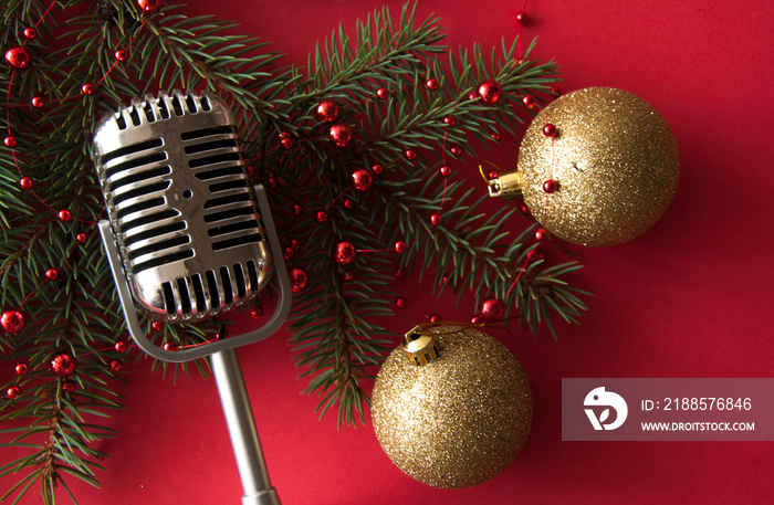 Microphone and fir branches against red lights, space for text.