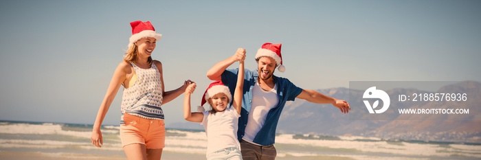 Happy family wearing Santa hat while enjoying at beach