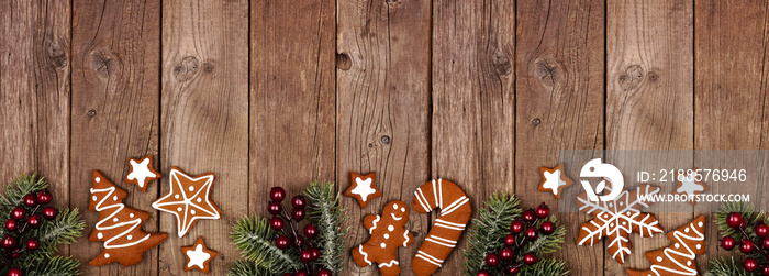 Christmas gingerbread cookies and tree branches. Top view border banner on a rustic wood background.