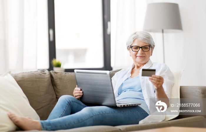 technology, online shopping and people concept - happy senior woman in glasses with laptop computer 
