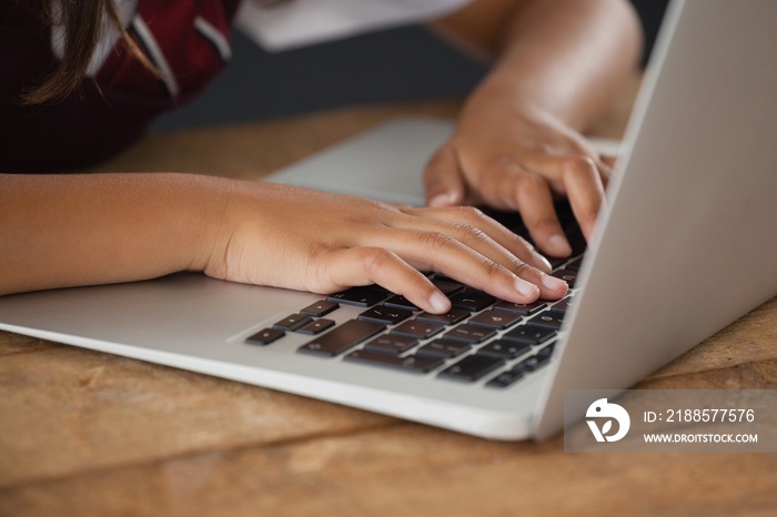 Schoolgirl using laptop against blackboard in classroom