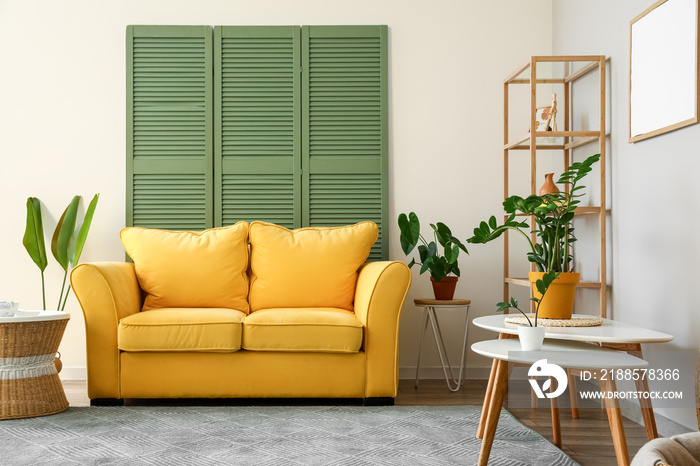 Interior of stylish living room with yellow sofa, coffee tables and houseplants