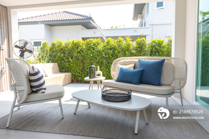 outdoor furniture rattan chairs, table and blue pillow by the home patio. Beautiful and cozy home ou
