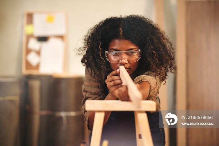 Young attractive african american female carpenter in wood working in small business workshop. Wood 