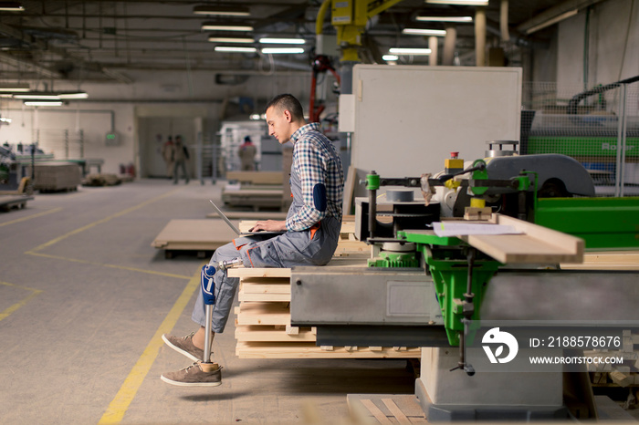 Disabled young man with an artificial leg is working at the furniture  factory