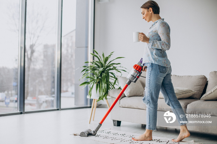 Woman with accumulator vacuum cleaner drinking coffee