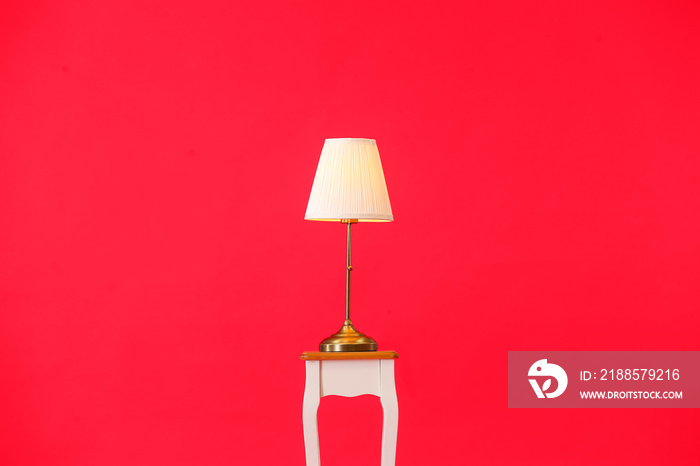 Stand with stylish lamp on color background