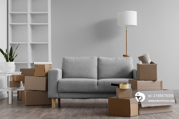 Cardboard boxes with grey sofa and lamp in living room on moving day