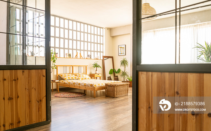 Spacious and bright boho-style bedroom, in an industrial loft, with wooden furniture: bed, night tab