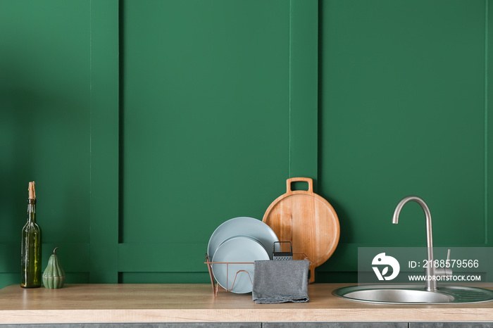 Plates, board and sink on counter top near green wall in kitchen