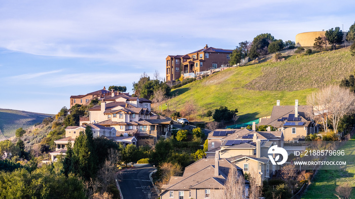 Residential neighborhood with multilevel single family homes, built on a hilly area; water tank visi