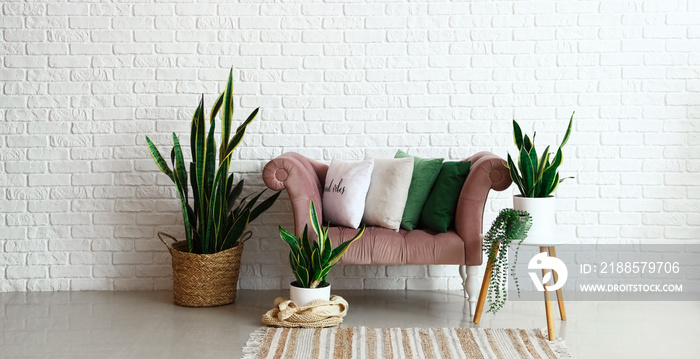 Stylish comfortable lounge with houseplants near white brick wall in room