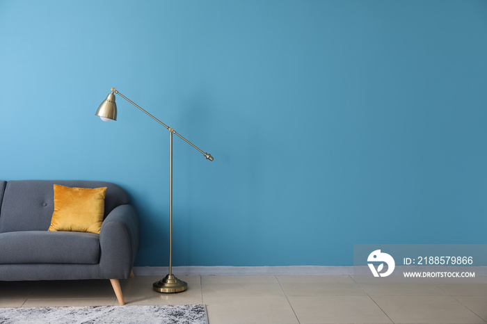 Golden standard lamp and sofa near blue wall