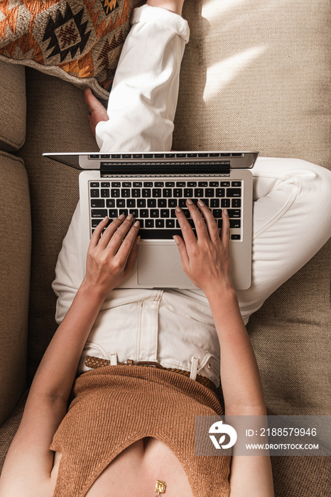 Young woman workin on laptop computer lying on the couch. Work at home at quarantine, freelancer con