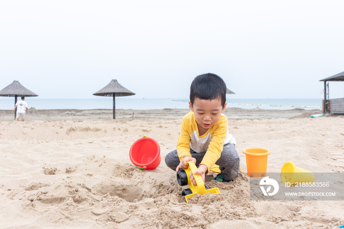 快乐的小男在海边玩沙子