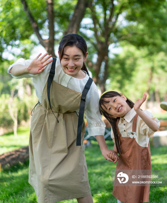 妈妈拉着女儿的手开心招手