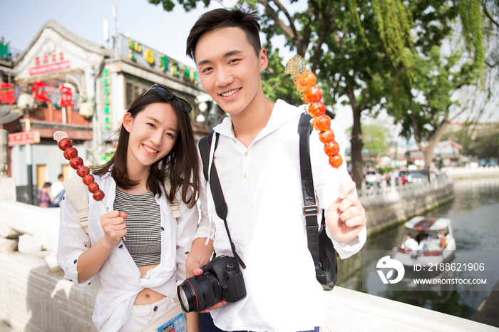 青年情侣旅游拿着糖葫芦