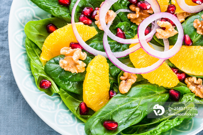 Salad with spinach leaves orange pomegranate and nuts.Light healthy vitamin salad bowl.