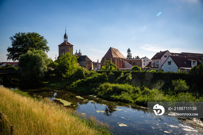 Seehausen in der Altmark, Sachsen-Anhalt, Deutschland. Der Fluss Aland fließt vorbei an der Alzkirche und dem Beuster Tor im Sommer. Hinten ist die Kirche St. Petri zu sehen.