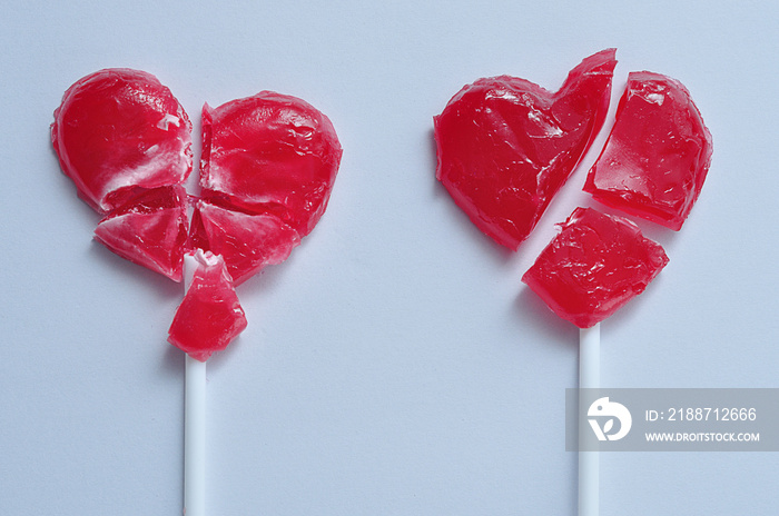 Two broken red heart lollipops symbolizing broken hearts