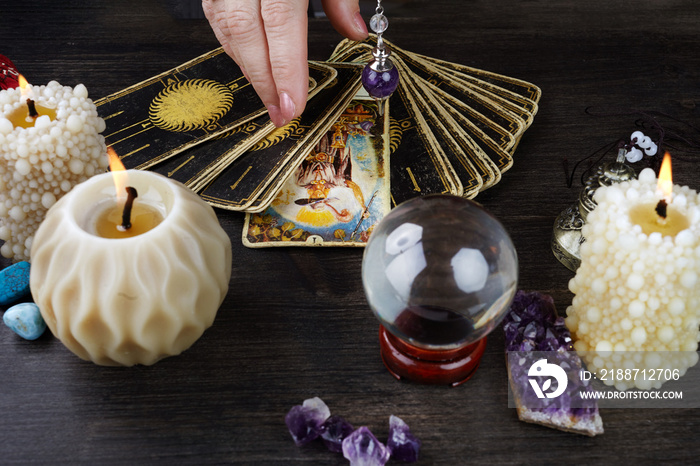 Still life with the tarot cards, magic stones and candles on wooden table. Fortune telling seance or magic ritual.