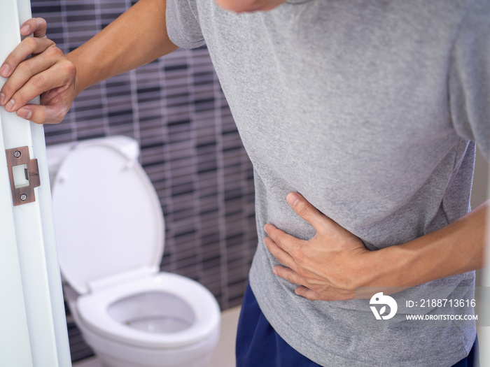 Men are standing in front of the bathroom door using their hands to hold the abdomen with severe abdominal pain or diarrhea. The concept of stomach cramps, diarrhea