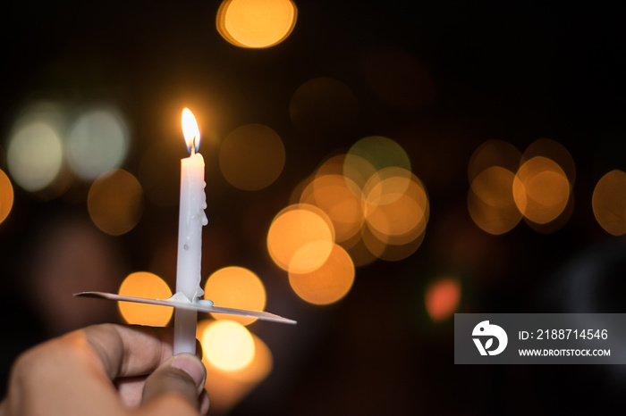 Blurred image for background of hand with candle memorable for King Bhumibol Adulyadej of thailand