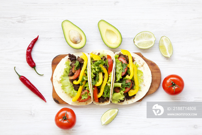 Tortillas with pork, vegetables, avocado,lime. White wooden background. Top view, flat, overhead.