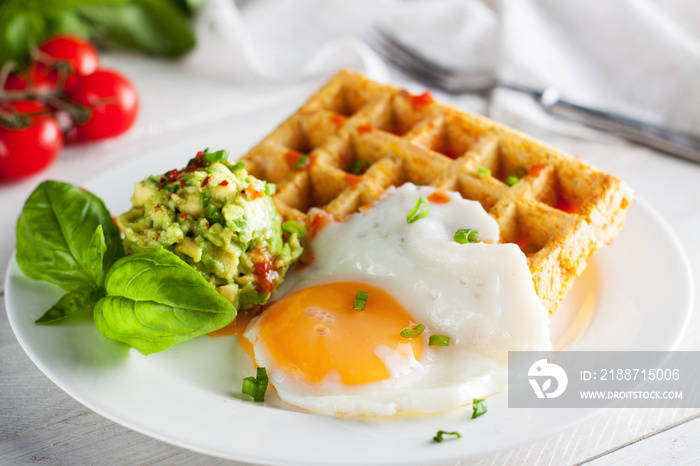 Fresh baked sweet potato waffles with fried egg and avocado dip. Healthy breakfast