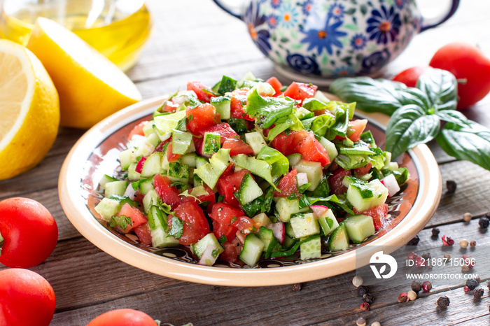 Delicious traditional Fattoush or bread salad with pita croutons, cucumber, tomato, lettuce and herbs on plate on table, easy and healthy authentic recipe