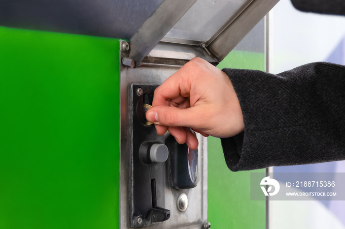 Close up of hand inserting coin into slot machine at car wash. Self service.