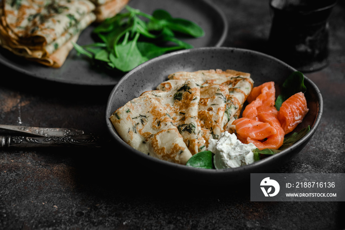 Thin pancakes with herbs, salmon and cream cheese on a plate. crepes