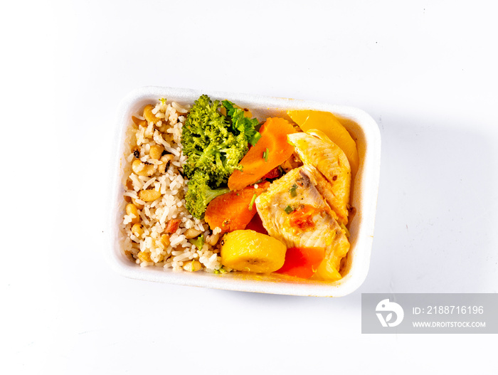 food delivery, lunch box with fish in sauce with boiled carrots, brocolis and bananas, brown rice and white beans isolated on white background, top view.