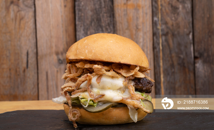 Monster burger. Multilayer hamburger with mozzarella cheese, meat, cucumber pickles, mayonnaise, lettuce and crispy onion.