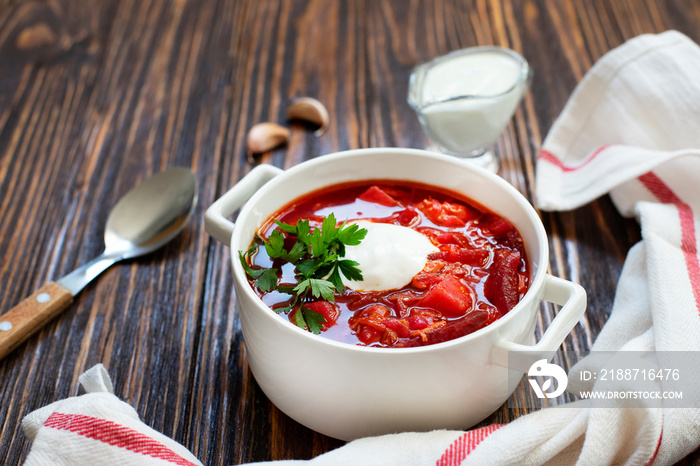 Borscht traditional beetroot soup, Ukrainian and Russian national cuisine. Borsch served in a white bowl with sour cream and parsley on a wooden table. Close-up