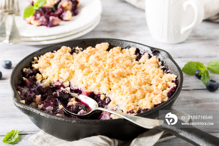 Coconut crumble in cast iron pan with fresh apples and blueberry. Healthy food concept.