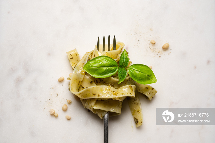 Fork with pasta, pesto and basil on marble background. Italian food, tagliatelle pasta. Close-up view