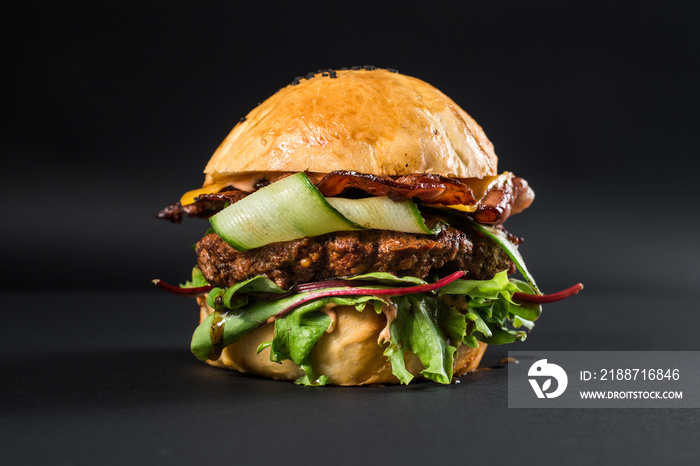 Tasty craft burger with grilled meat, cheese, tomato on the black background