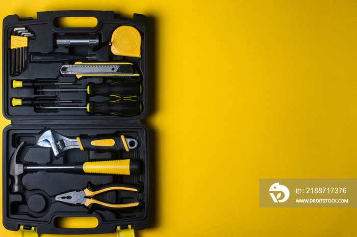 A set of hand tools in a plastic box on a yellow background.