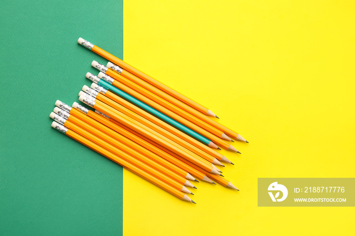 Green pencil among orange ones on color background. Concept of uniqueness