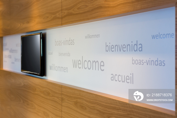 A welcoming office foyer with signage in multiple languages with flat screen TV