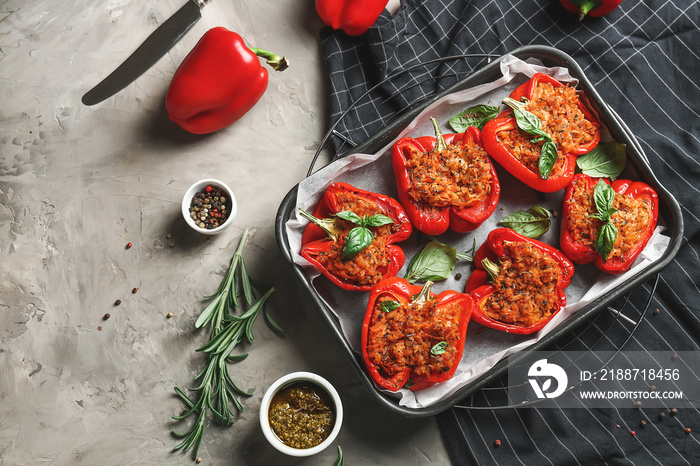 Baking dish with tasty stuffed pepper and sauce on grey background