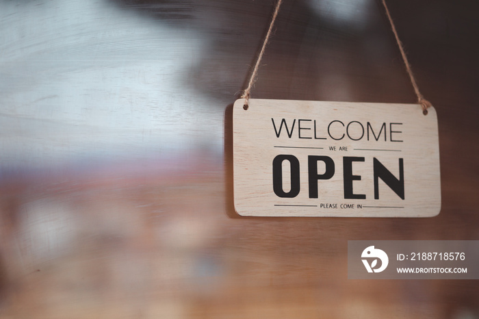 A coffee shop with a welcome sign posted through the glass door, ready to serve customers.