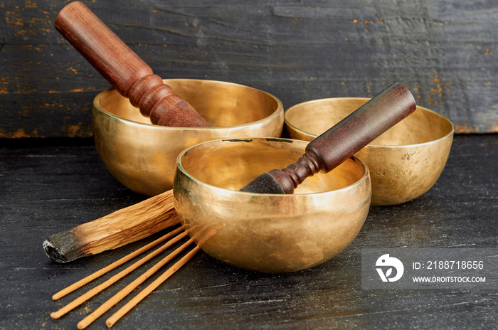 Tibetan singing bowls with palo santo and aroma sticks on the dark background.  Nepal music instruments for meditation, relaxation after yoga practice and healing massage
