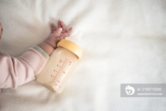 Baby hand and Bottle of Mother breast milk on white blanket background for text space