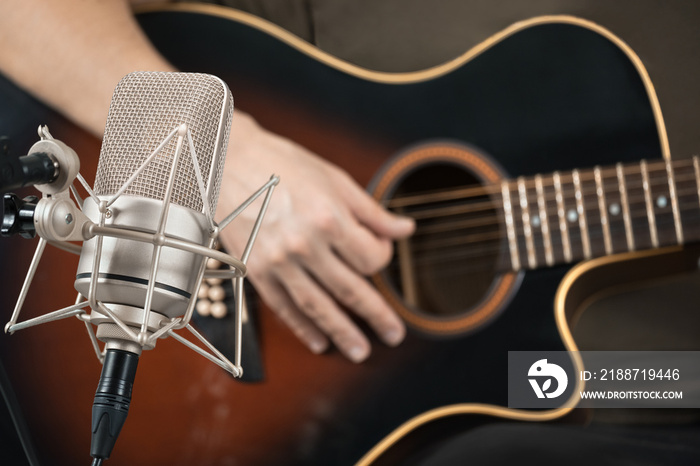 Microphone recording an acoustic guitar played by hand